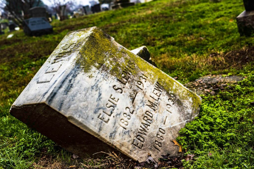 a grave in the grass with a headstone in the background