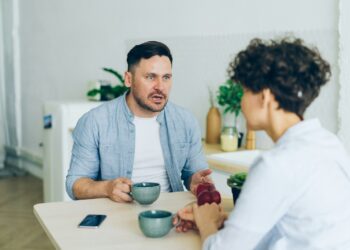 a man sitting at a table talking to a woman