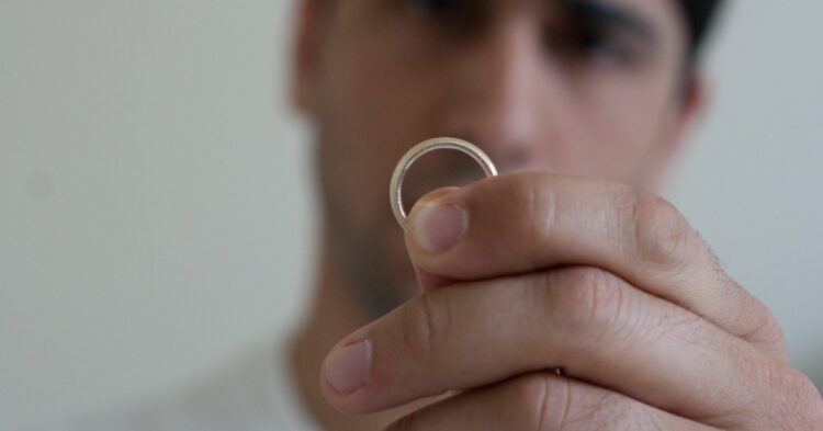 Man holding up a marriage ring (Eric Mesa via Flickr)