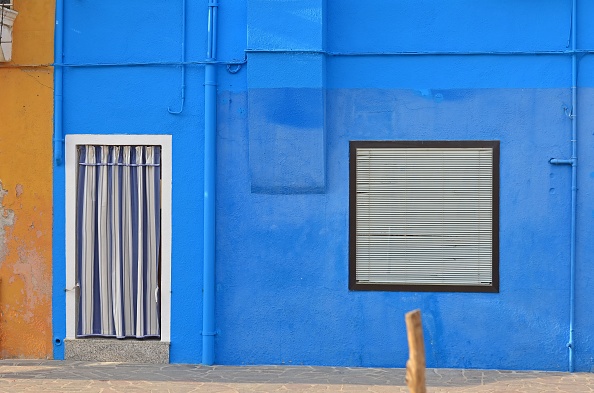 House with blue wall and blue curtains in front of the door