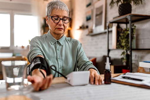 A senior woman measures blood pressure at her home.