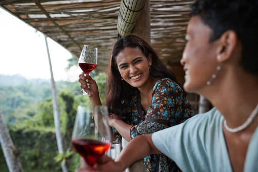 Happy woman enjoying wine with friend during vacation