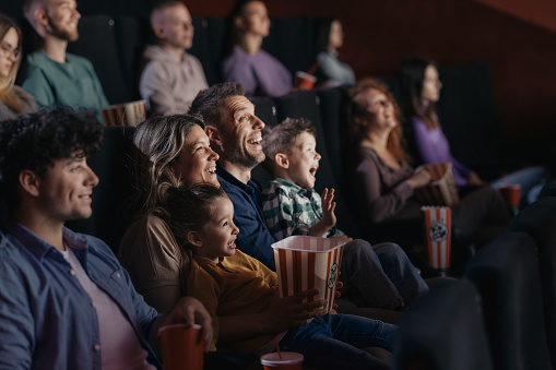 Cheerful family watching a funny movie in theatre.