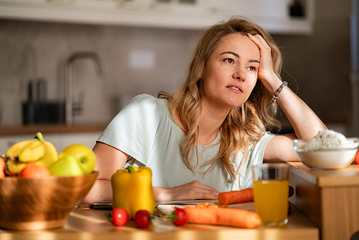A tired woman is trying to prepare lunch while sitting in the kitchen