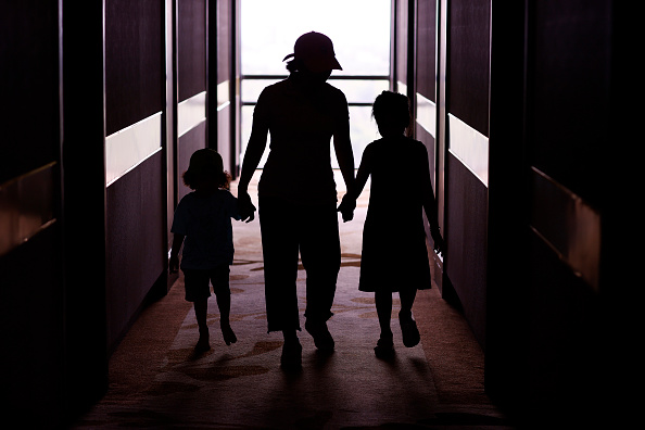 Adult with children. Silhouette. Woman holding hands of boy and girl. One parent family concept