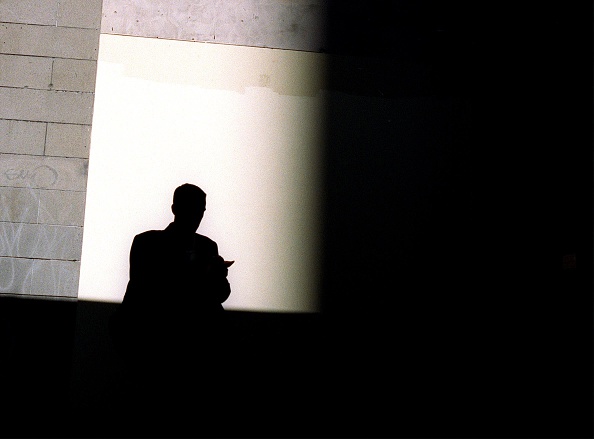 A silhouetted man sits in the shadows, 18 July 2002. AFR Picture by TAMARA VONI