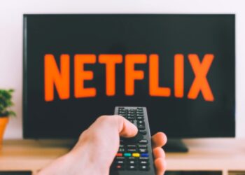 a hand holding a remote pointing at a tv