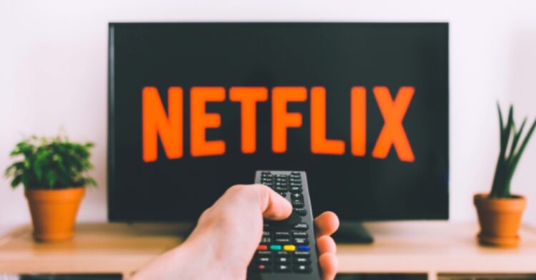 a hand holding a remote pointing at a tv