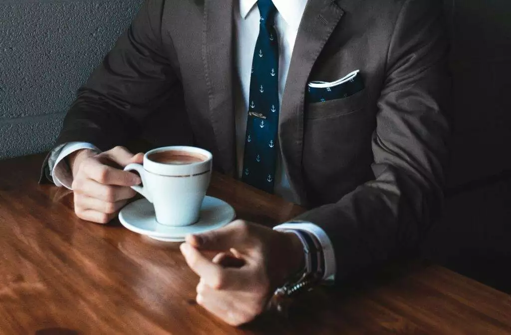 Man wearing suit holding coffee (Unsplash | Andrew Neel)