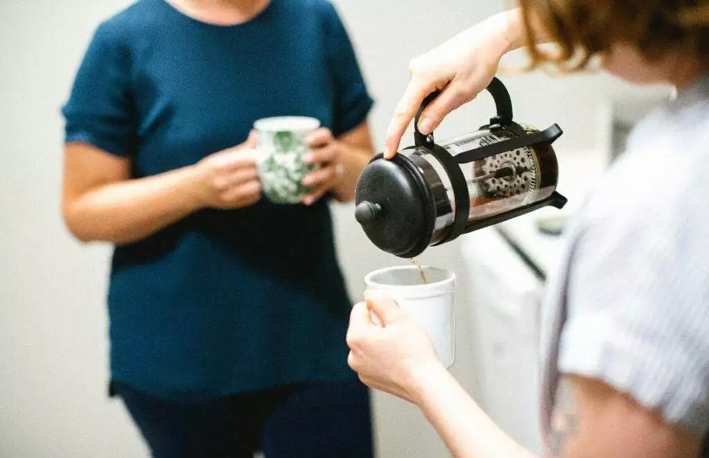 Person pouring coffee in office kitchen (Unsplash | Mad Fish Digital)