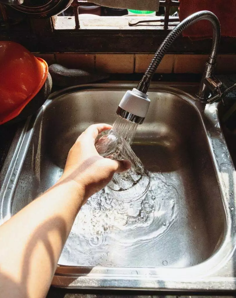 Person washing glass in sink (Unsplash | Ivan Samudra)