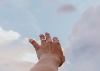 hand reaching out to the clouds in the sky