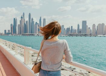 A woman standing on a bridge looking at the city