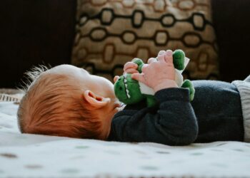 baby lying on white bed