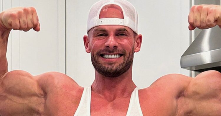 Bodybuilder Joey Swoll posing in a gym, showcasing his muscular physique with gym equipment