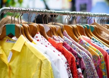 A stack of second-hand clothes, showcasing vintage shirts and jackets, emphasizing the need for hygiene precautions.
