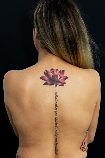A young woman's back with a lotus flower tattoo