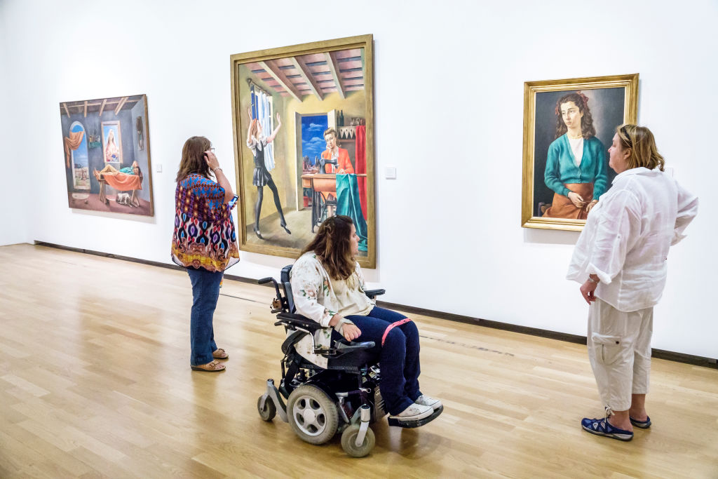 A girl in an electric wheelchair looking at Antonio Berni paintings at the National Museum of Fine Arts.