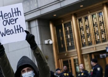 Protester in New York City holding 'health over wealth' sign (Photo by Reuters)