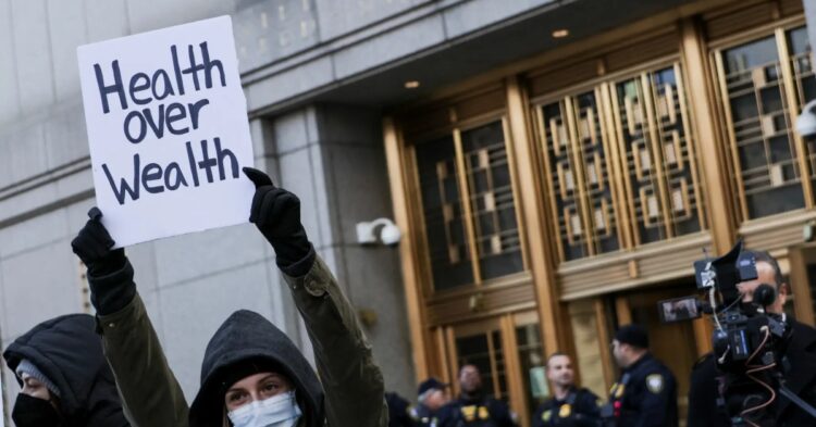 Protester in New York City holding 'health over wealth' sign (Photo by Reuters)