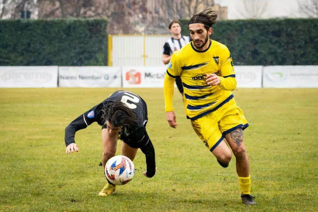 Dramatic capture of soccer players during a competitive match on a rainy day.
