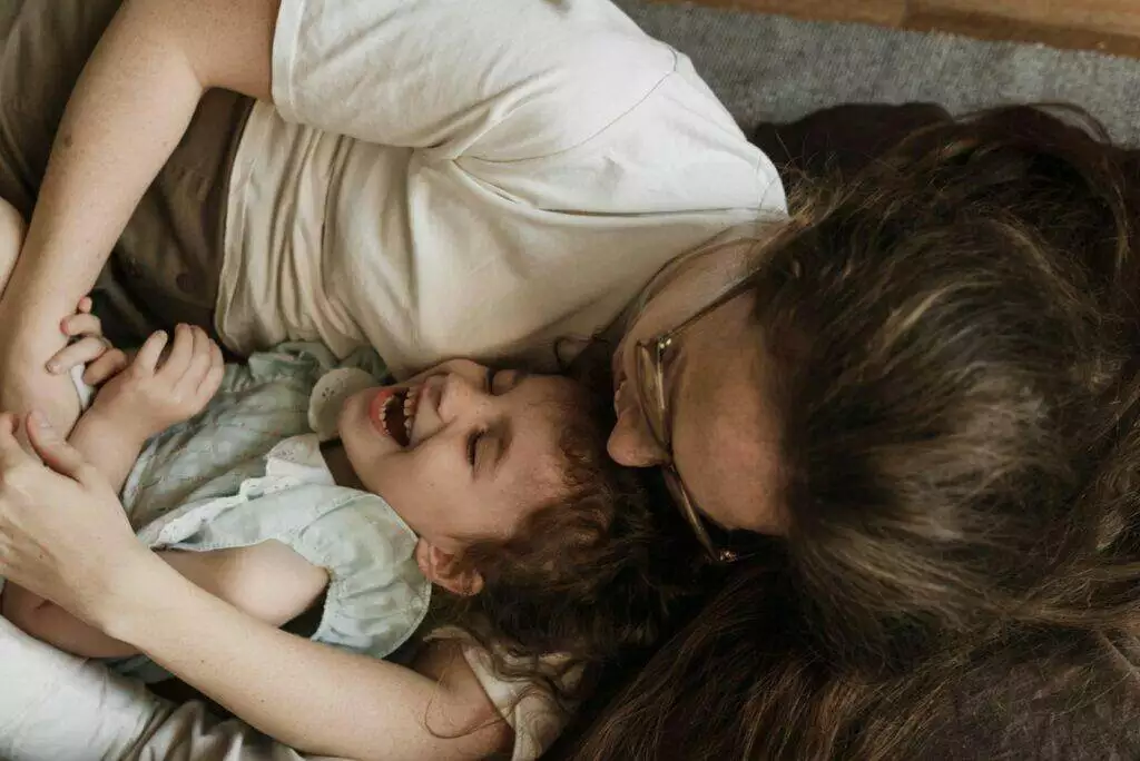 A loving mother embracing her laughing daughter, capturing a moment of joy and togetherness.