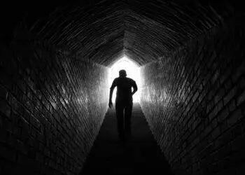 Man standing in a tunnel with light at the end (Unspalsh | Mahdi Dastmard)