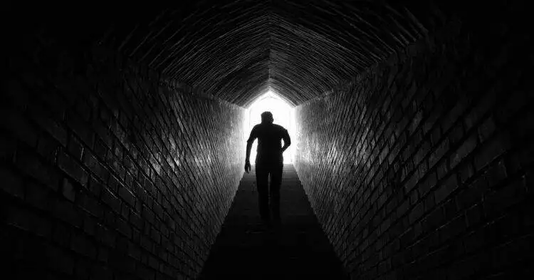Man standing in a tunnel with light at the end (Unspalsh | Mahdi Dastmard)