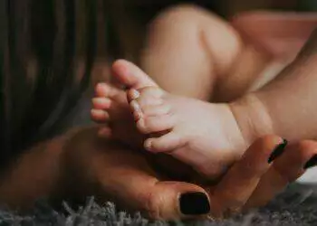 Mother holding baby's feet (Unsplash | Alex Pasarelu)