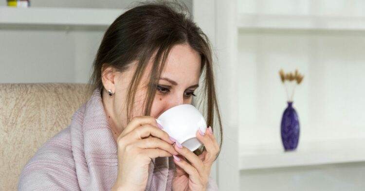 Woman sitting in a chari drinking from a mug (Unsplash | Bermix Studio)