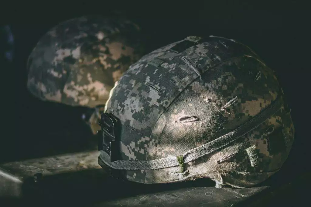 gray and brown camouflage nutshell helmet on table