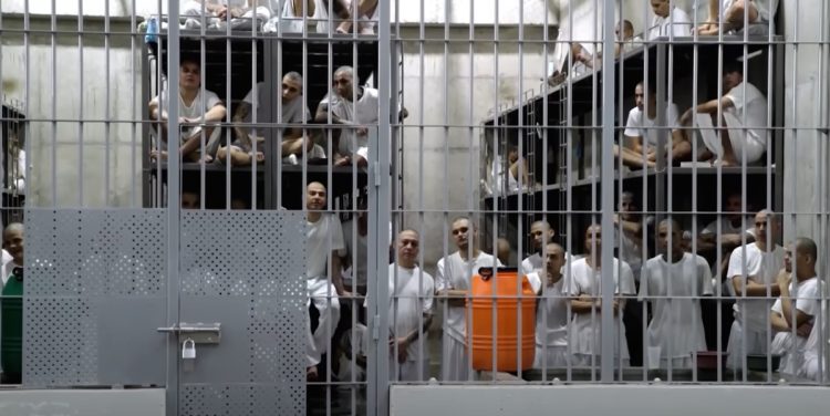 Prisoners standing behind bars in 'World's Worst Prison' CECOT