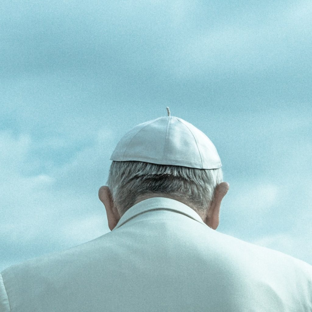 person wearing white cap looking down under cloudy sky during daytime