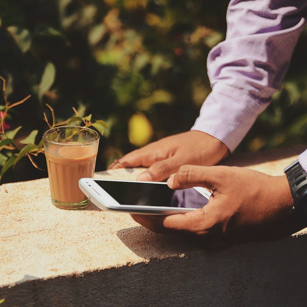 man using smartphone beside drinking glass