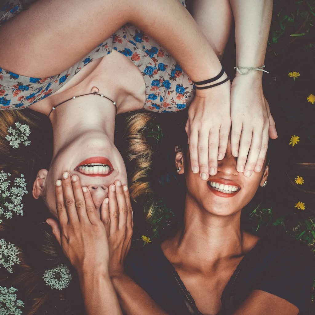 man and woman smiling while laying on lawn field