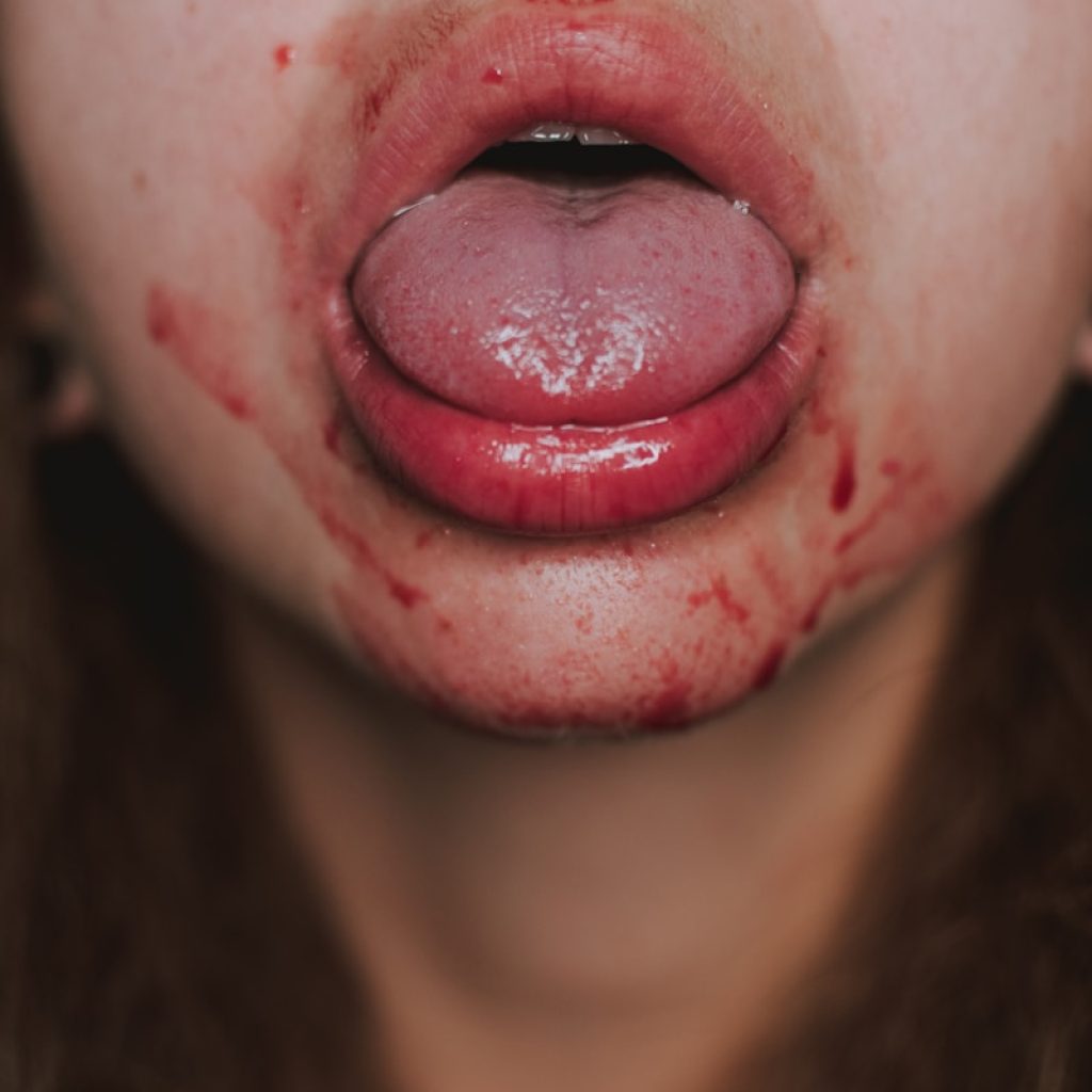 woman with red lipstick showing her tongue