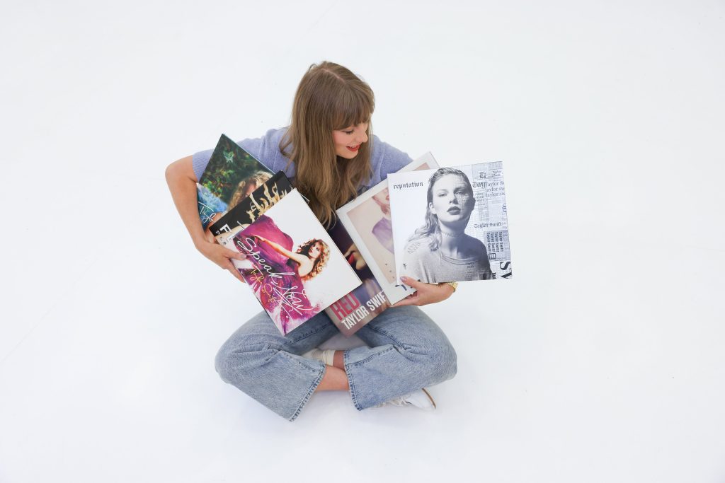 Taylor Swift holding her first six albums