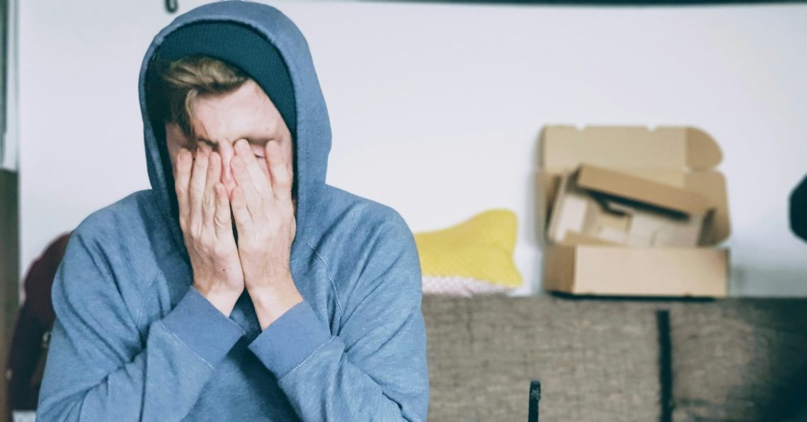 Man sitting with both hands on his face