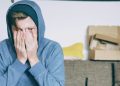 Man sitting with both hands on his face