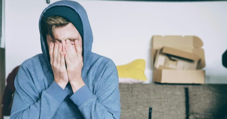 Man sitting with both hands on his face