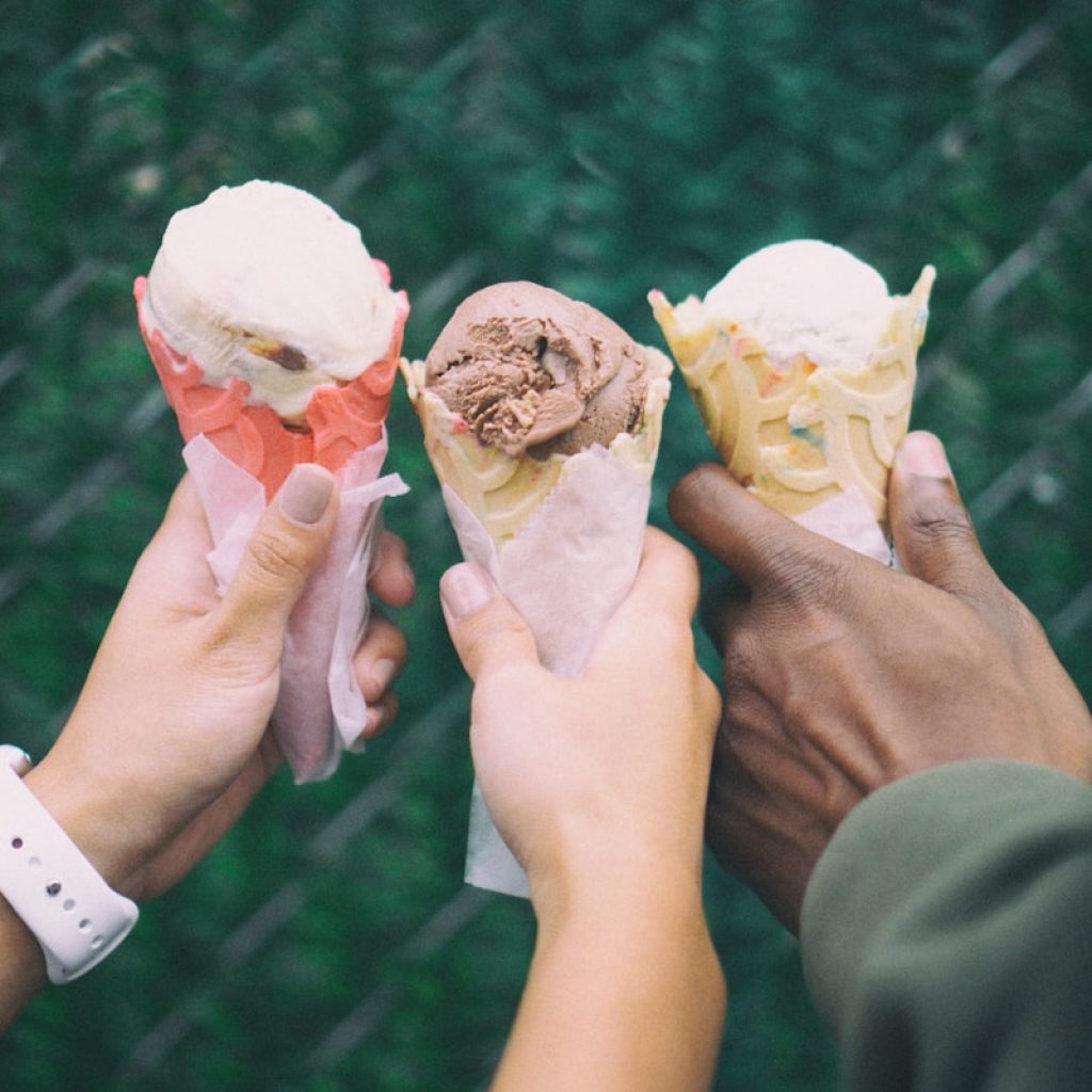 three people holding ice cream cones in their hands