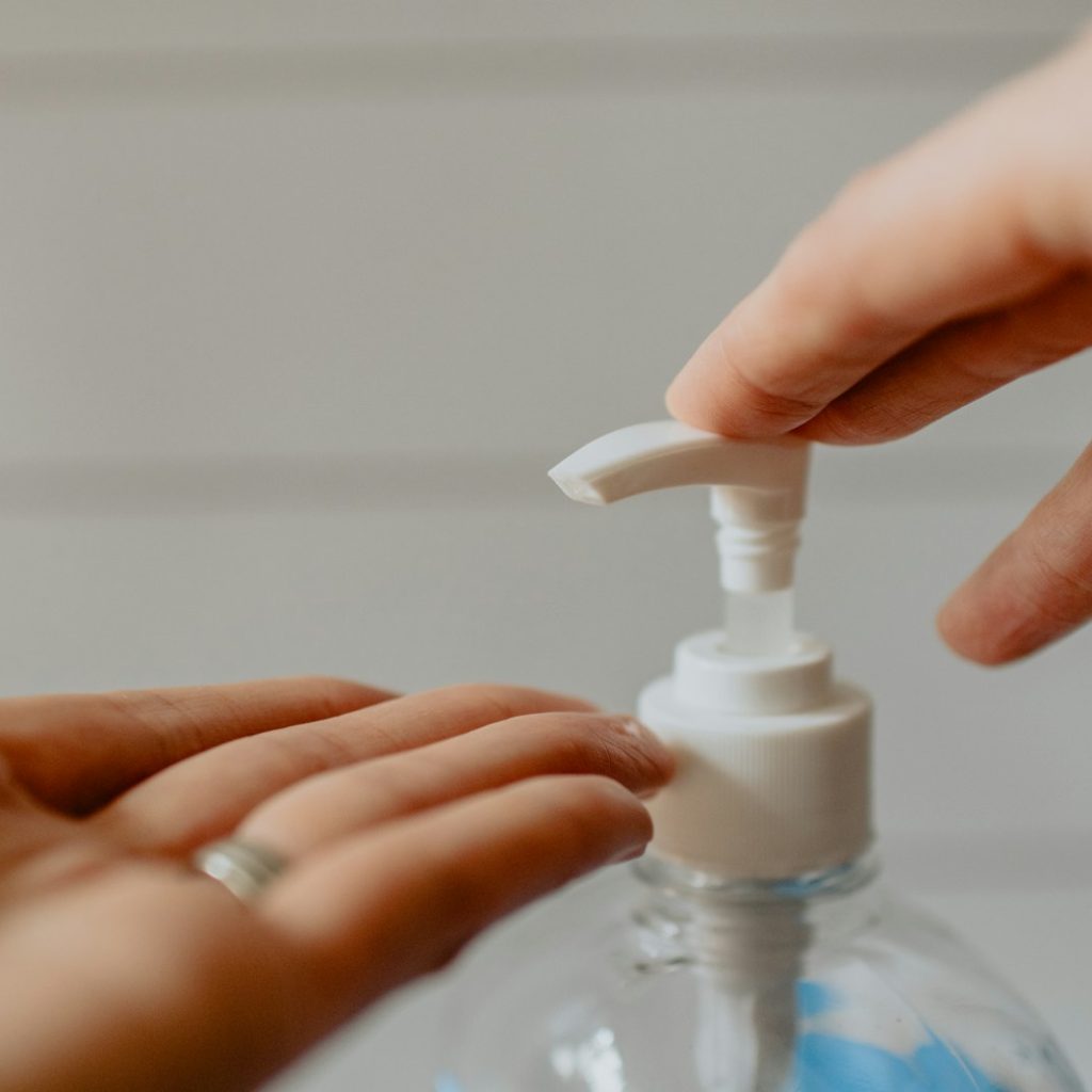 person holding white plastic pump bottle