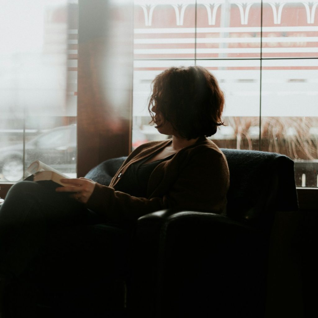 woman in black and brown plaid long sleeve shirt sitting on black sofa