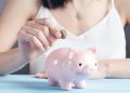 Woman putting coin in piggy bank