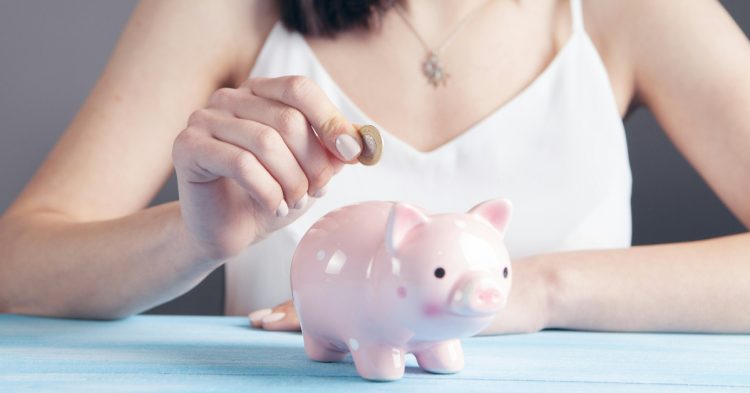 Woman putting coin in piggy bank