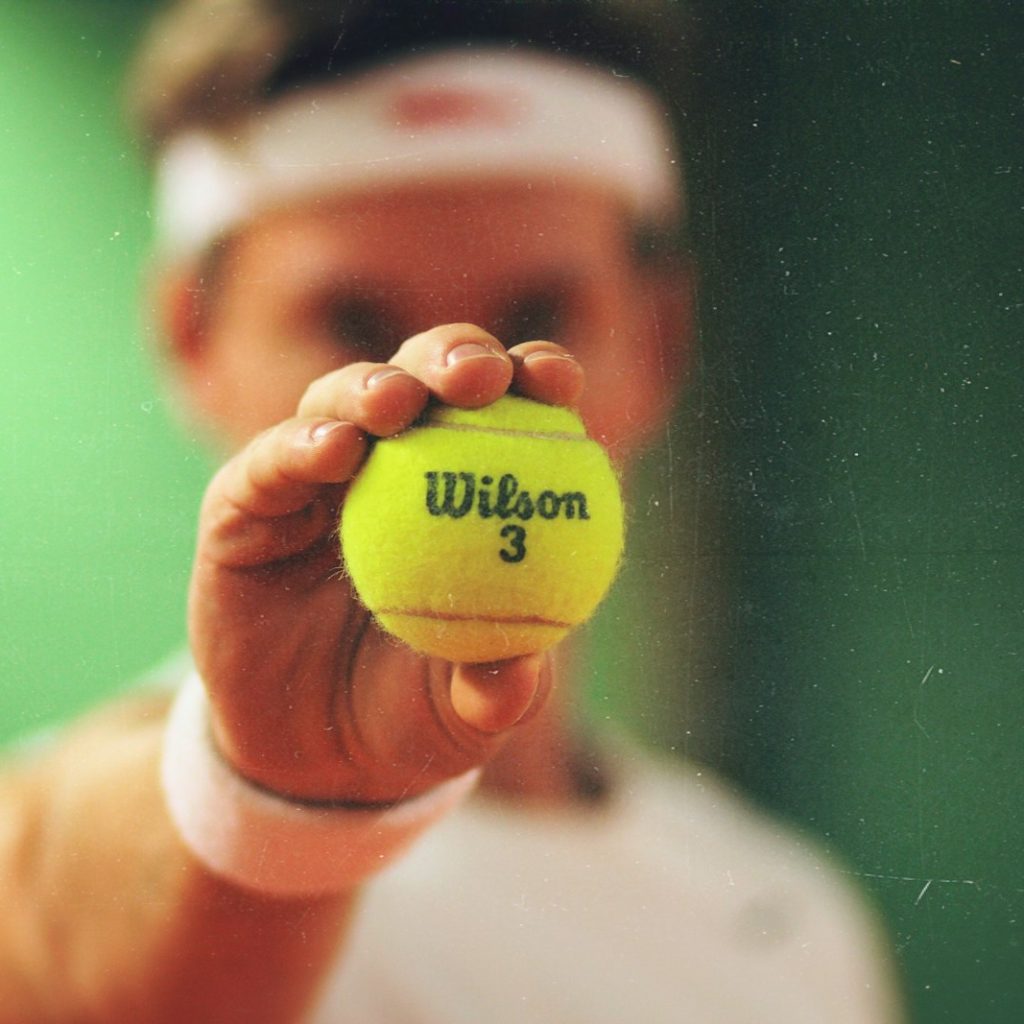 person holding green Wilson tennis ball